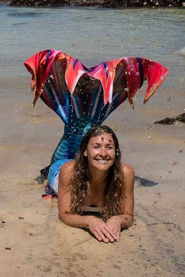 Merman with rainbow tail on the beach